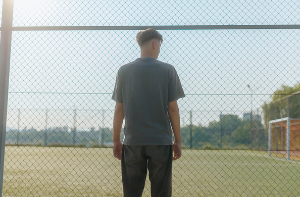 man standing behind fence