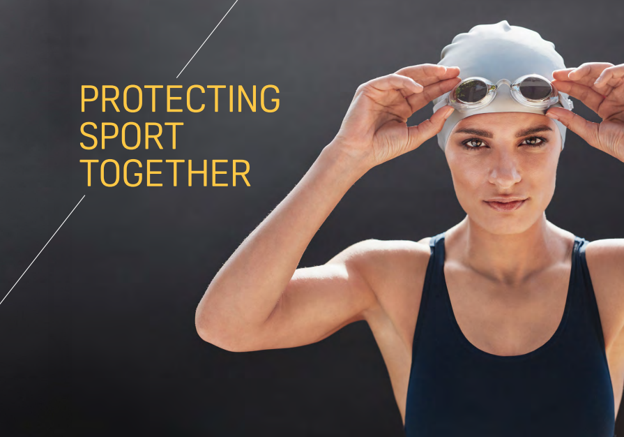 Swimmer in dark blue bathing suit and silver swimming cap putting goggles on