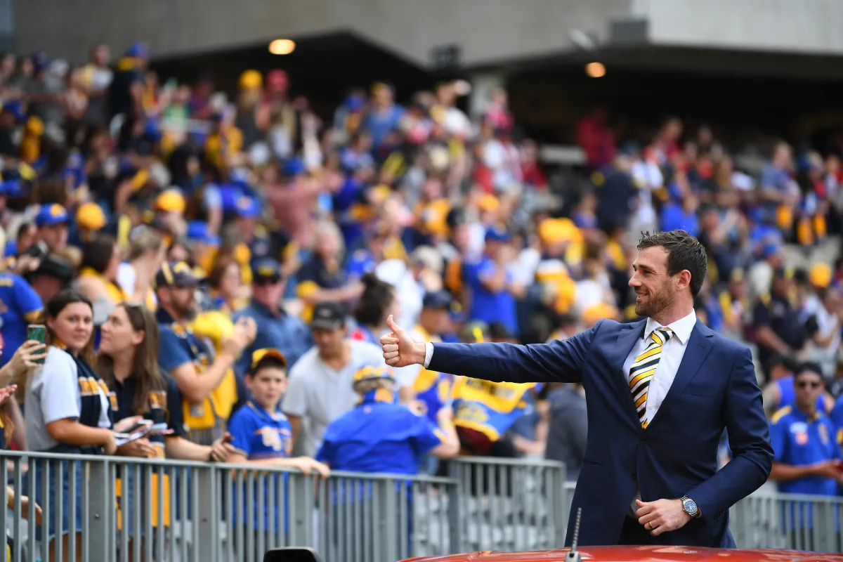Eric Mackenzie waving to crowd at an AFL match