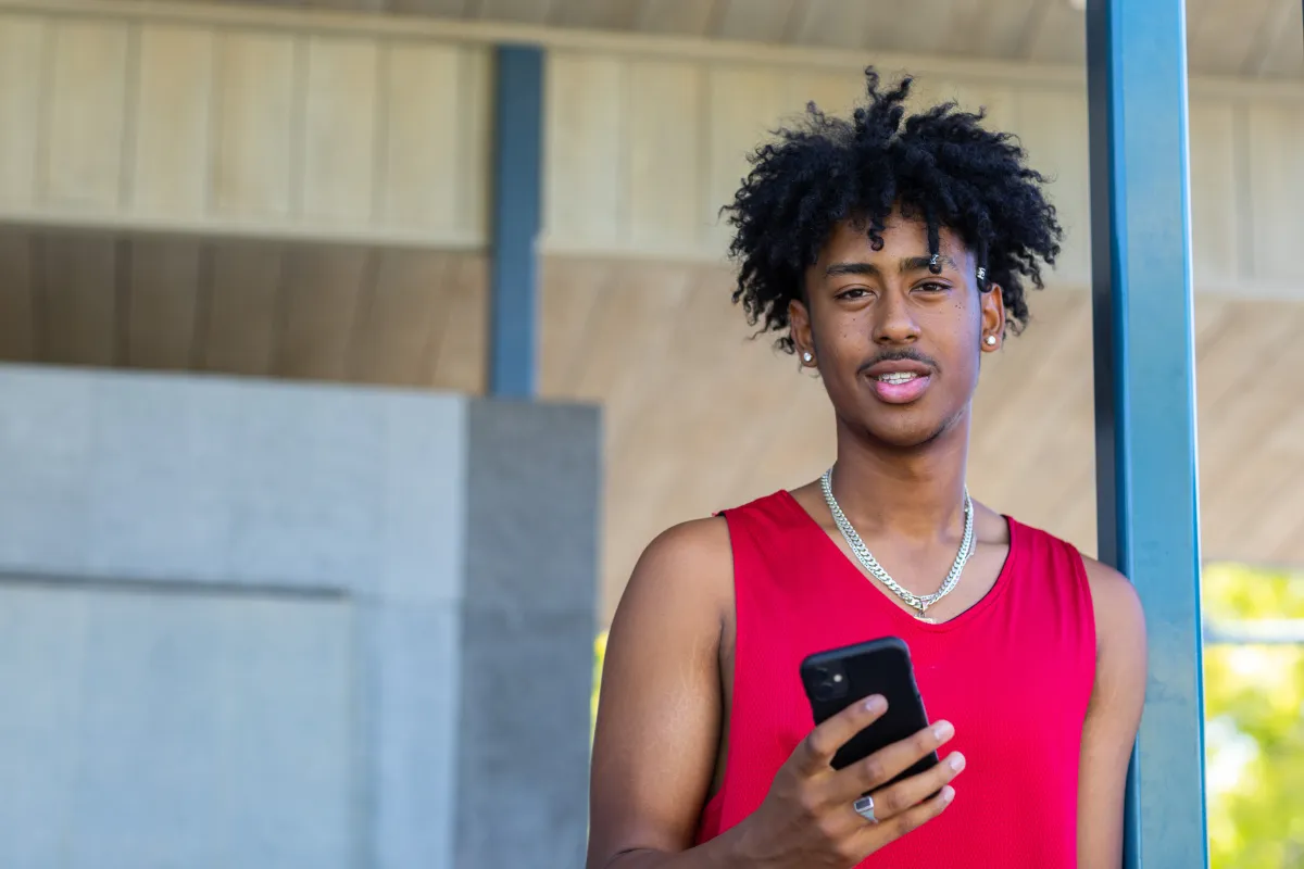 Young Australian basketballer in a red singlet hold phone in hand